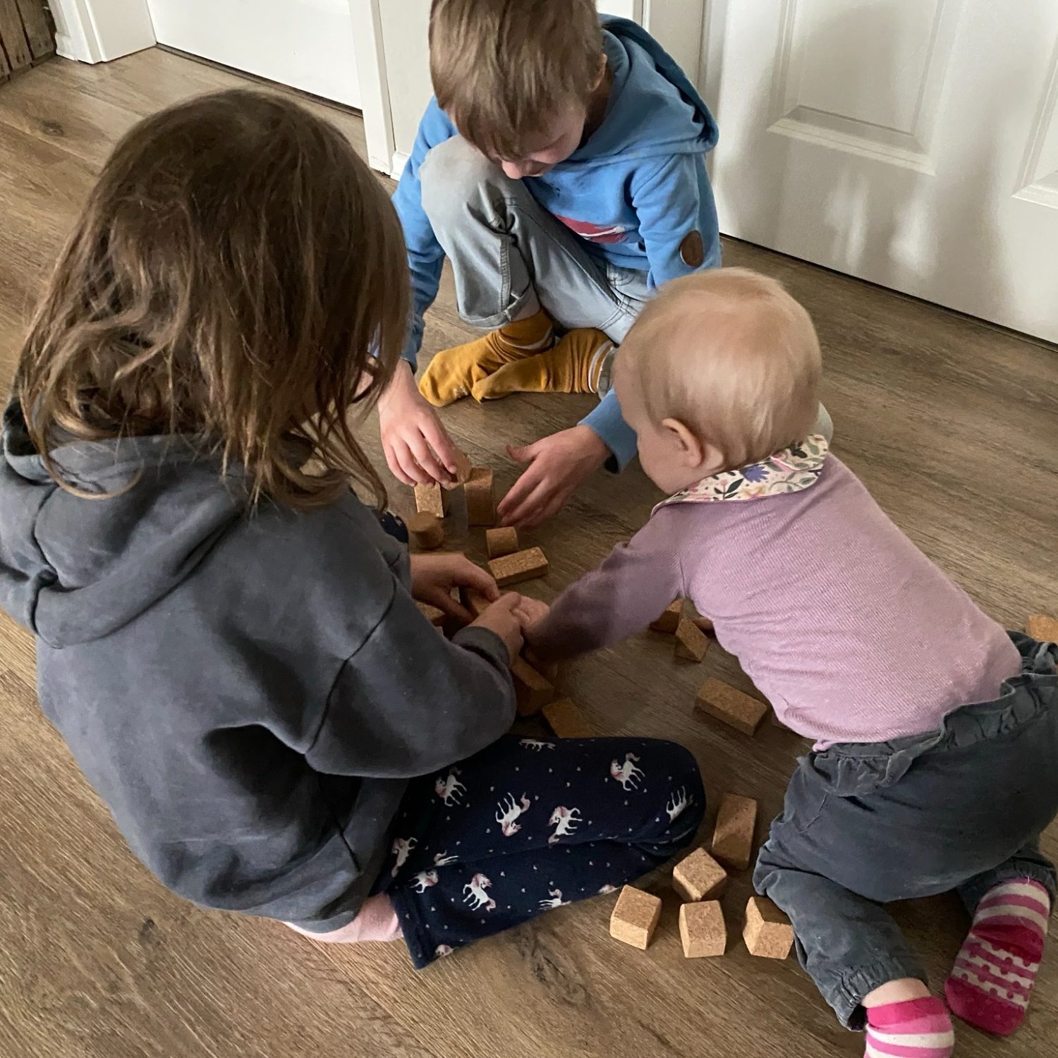 Mehrere Kinder spielen gemeinsam mit Korkino Korkbausteinen aus Naturkork. Das nachhaltige Spielmaterial eignet sich für verschiedene Altersgruppen und fördert gemeinsames, kreatives Spielen in Familie, Kita und Kindergarten.